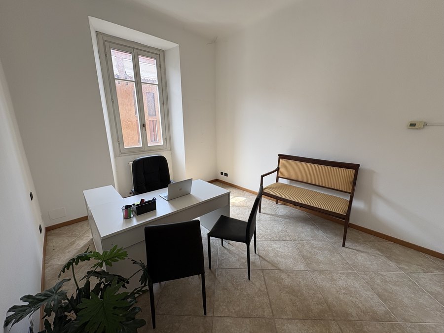 Sala colloqui dell'agenzia immobiliare a Como con scrivania e seduta per i clienti